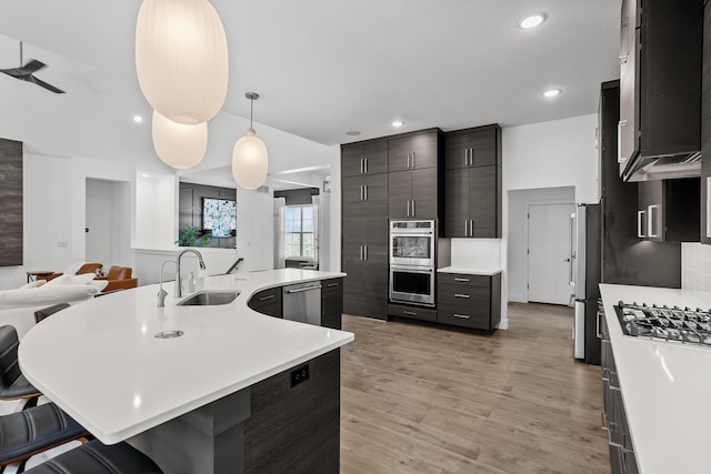 kitchen with a breakfast bar, open floor plan, decorative light fixtures, light countertops, and a sink