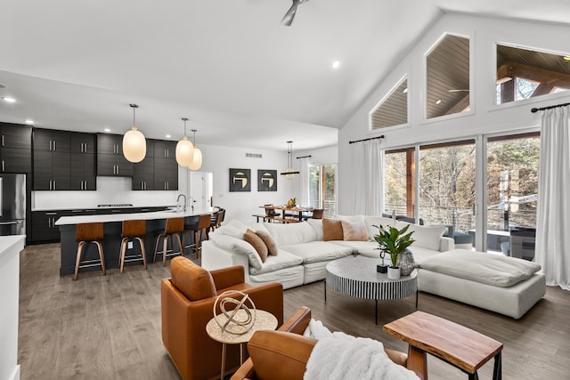 living area featuring high vaulted ceiling, recessed lighting, dark wood-style flooring, and visible vents