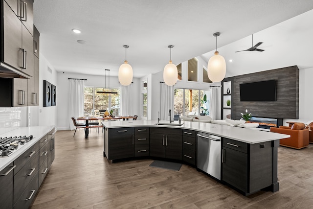 kitchen featuring decorative light fixtures, light countertops, appliances with stainless steel finishes, open floor plan, and a sink