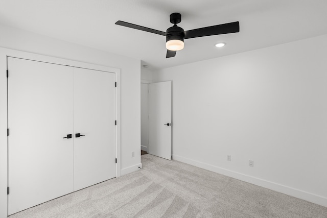 unfurnished bedroom with a ceiling fan, baseboards, a closet, and light colored carpet