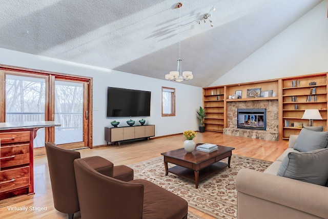 living room with baseboards, an inviting chandelier, light wood-style flooring, a fireplace, and a textured ceiling