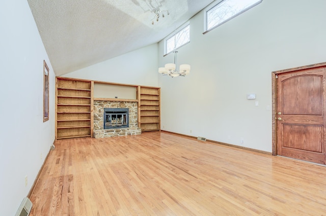 unfurnished living room with baseboards, light wood-style flooring, a fireplace, a textured ceiling, and high vaulted ceiling