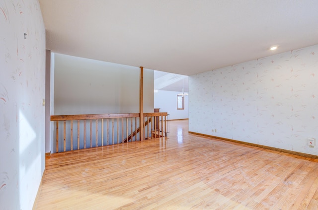 unfurnished room with baseboards, wood finished floors, and wallpapered walls