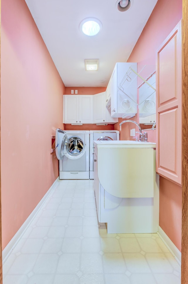 clothes washing area with washing machine and clothes dryer, cabinet space, light floors, and baseboards