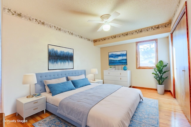 bedroom with a ceiling fan, a textured ceiling, a closet, light wood-style floors, and baseboards