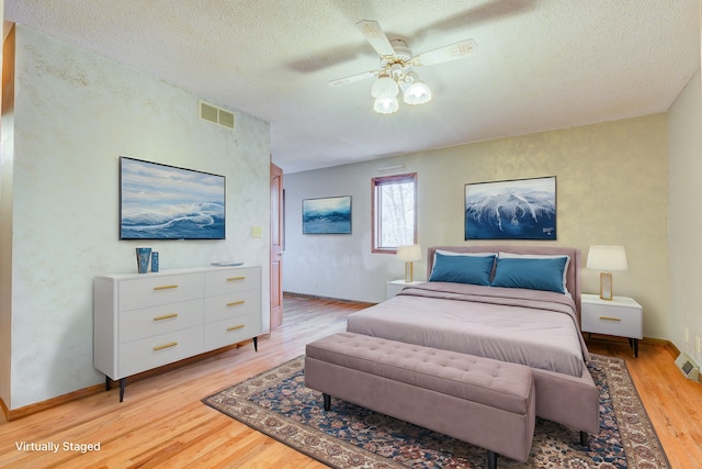 bedroom with a ceiling fan, baseboards, visible vents, light wood finished floors, and a textured ceiling