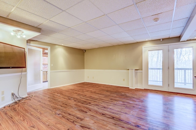 spare room with wood finished floors, baseboards, and a drop ceiling