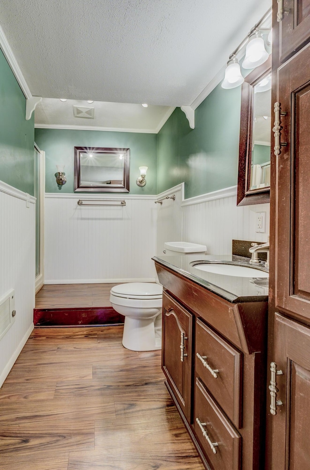 bathroom featuring toilet, vanity, wainscoting, wood finished floors, and a textured ceiling