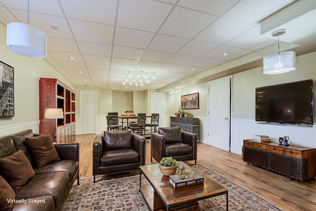 living area featuring a paneled ceiling and wood finished floors