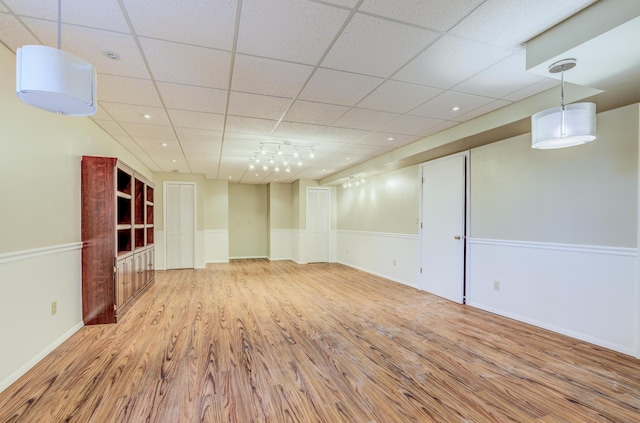 basement with wood finished floors, baseboards, and a drop ceiling