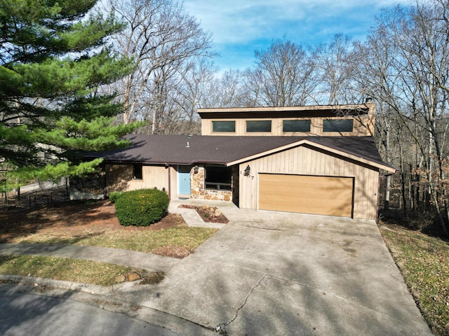 mid-century modern home with a garage, stone siding, and driveway