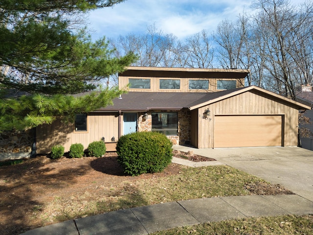 mid-century modern home featuring stone siding, driveway, and a garage