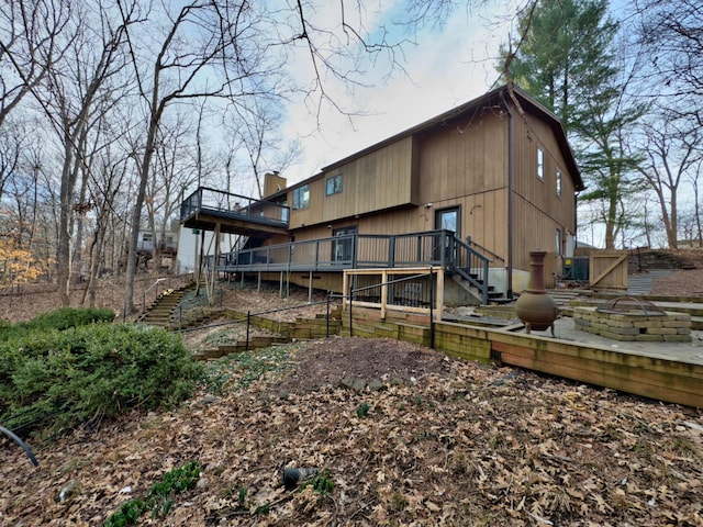 rear view of property featuring stairs, a deck, and an outdoor fire pit