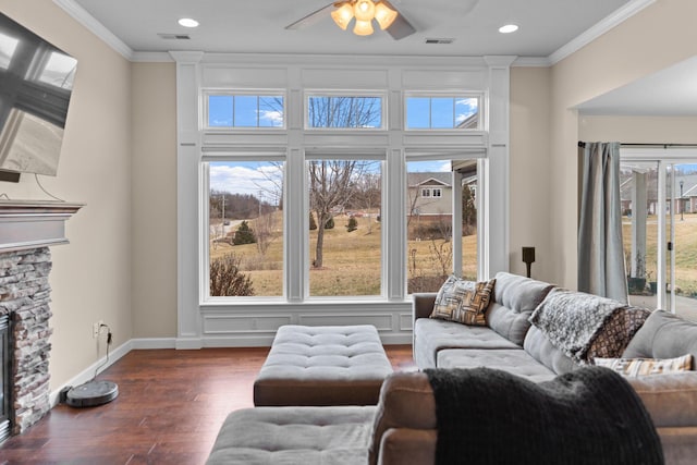 living room featuring crown molding, a fireplace, and plenty of natural light