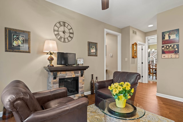 living area with a fireplace, visible vents, a ceiling fan, wood finished floors, and baseboards