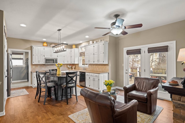 living room featuring light wood-style flooring, baseboards, ceiling fan, and recessed lighting