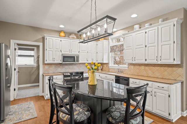 kitchen featuring white cabinets, dark stone counters, a kitchen island, a kitchen breakfast bar, and stainless steel appliances