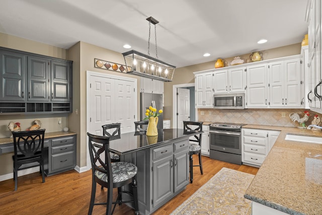 kitchen featuring a kitchen island, appliances with stainless steel finishes, a breakfast bar area, light stone countertops, and a sink