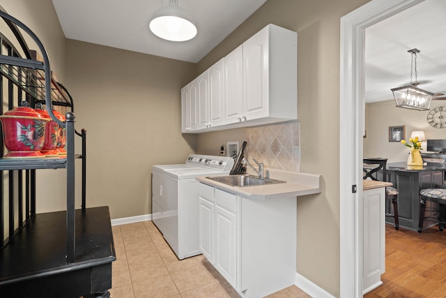 clothes washing area featuring light tile patterned floors, a sink, baseboards, independent washer and dryer, and cabinet space