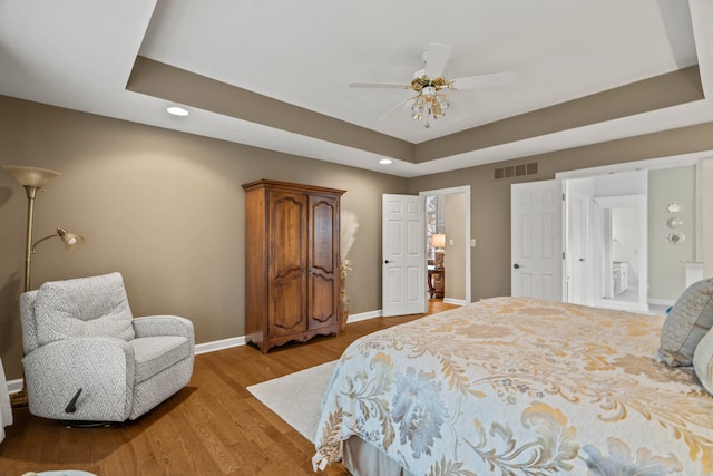 bedroom featuring recessed lighting, visible vents, baseboards, a tray ceiling, and light wood finished floors