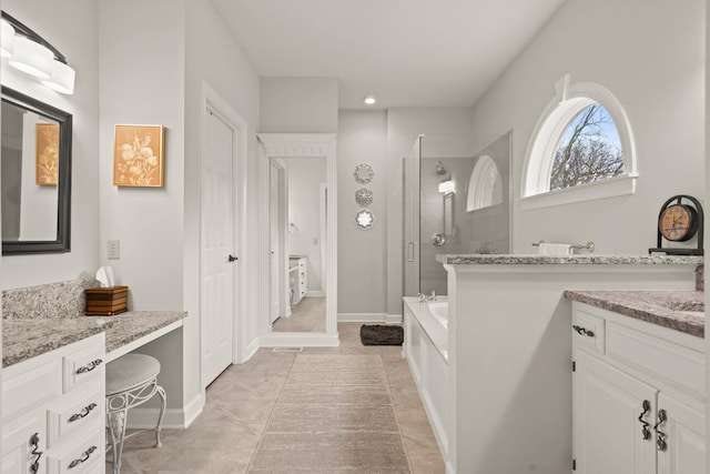 full bathroom with a stall shower, a garden tub, vanity, and baseboards