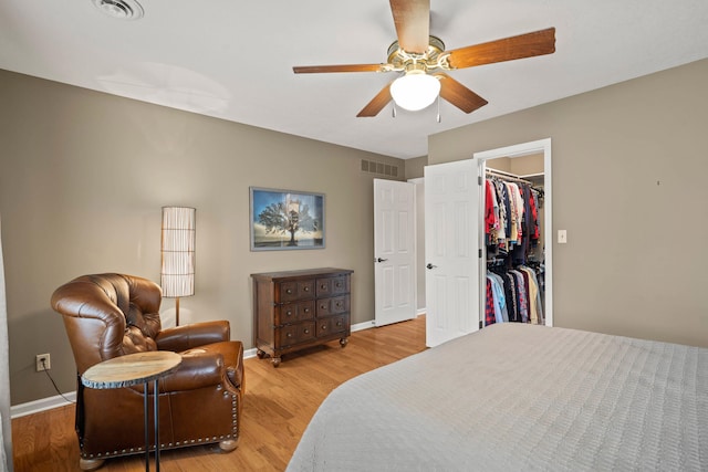 bedroom featuring light wood-style floors, a walk in closet, visible vents, and baseboards