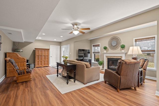 living area featuring baseboards, a tile fireplace, ceiling fan, light wood-type flooring, and recessed lighting