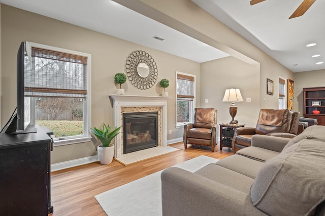 living room featuring light wood-type flooring, a wealth of natural light, visible vents, and baseboards