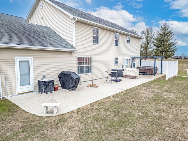 back of house featuring a hot tub, a pergola, a patio area, and a lawn