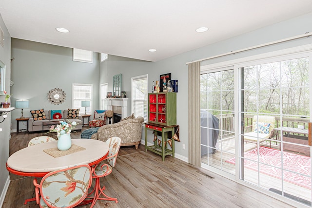 dining area featuring plenty of natural light, baseboards, light wood-style floors, a fireplace, and recessed lighting
