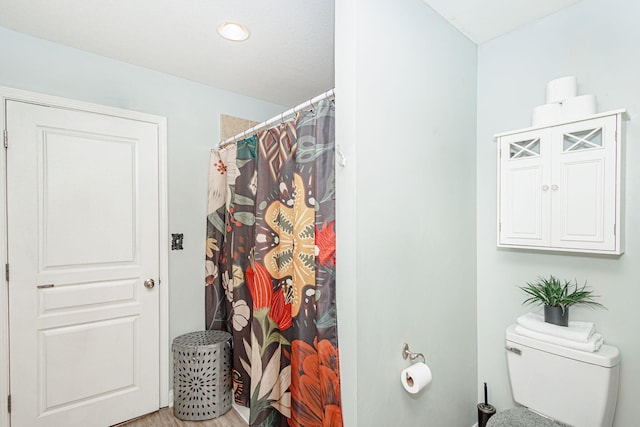 bathroom featuring toilet, wood finished floors, and a shower with curtain