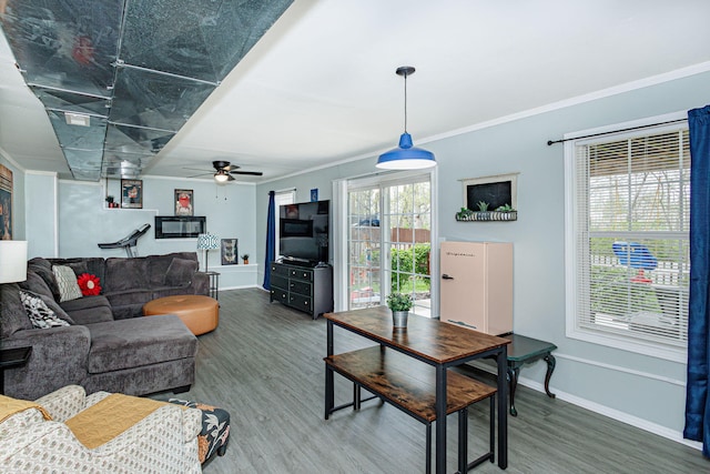 living room with wood finished floors, crown molding, baseboards, and ceiling fan