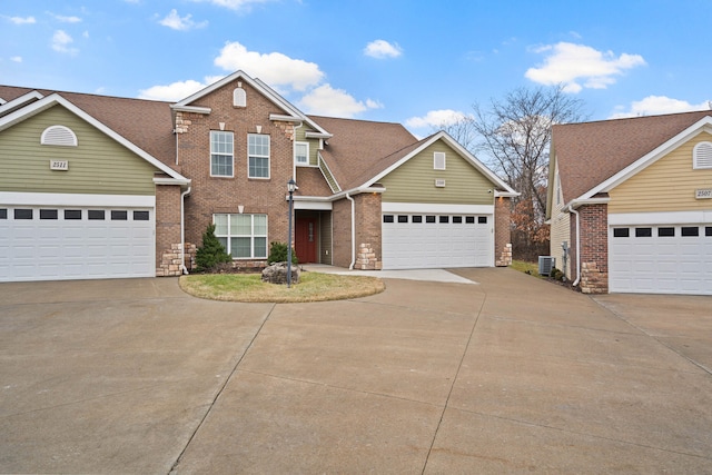 traditional-style home featuring driveway, a garage, central AC unit, and brick siding