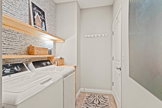 washroom featuring light tile patterned floors, laundry area, washing machine and dryer, and baseboards