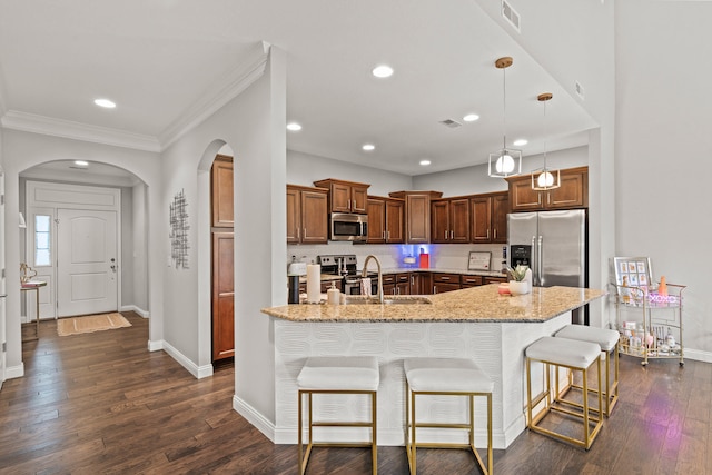 kitchen with arched walkways, a sink, visible vents, appliances with stainless steel finishes, and a kitchen bar