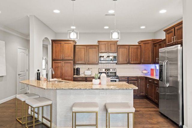 kitchen featuring tasteful backsplash, dark wood-type flooring, stainless steel appliances, a kitchen bar, and a sink