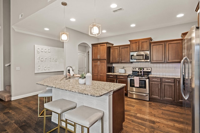 kitchen with a center island with sink, visible vents, dark wood-type flooring, stainless steel appliances, and backsplash