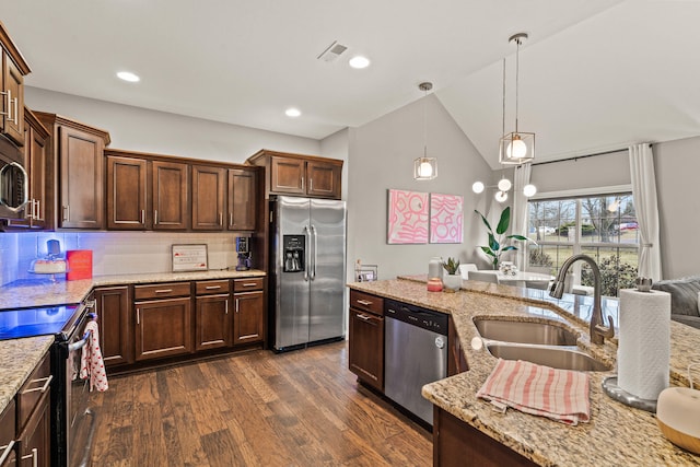 kitchen with lofted ceiling, stainless steel appliances, a sink, light stone countertops, and dark wood finished floors