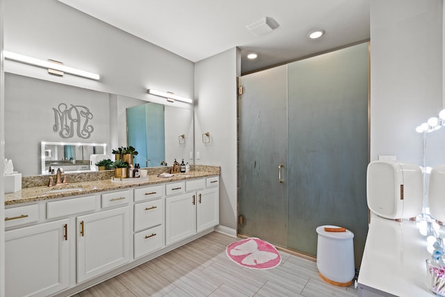 bathroom with double vanity, a stall shower, visible vents, and a sink