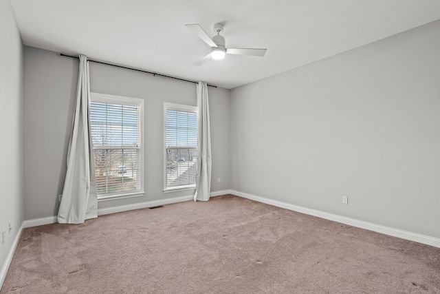 carpeted empty room featuring a ceiling fan, visible vents, and baseboards