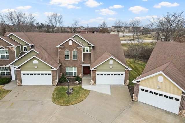 traditional-style home with concrete driveway, brick siding, roof with shingles, and an attached garage