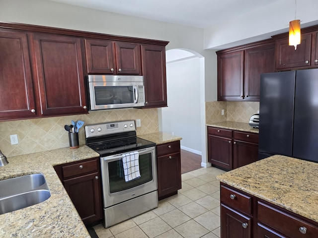 kitchen featuring light stone counters, sink, decorative light fixtures, and appliances with stainless steel finishes