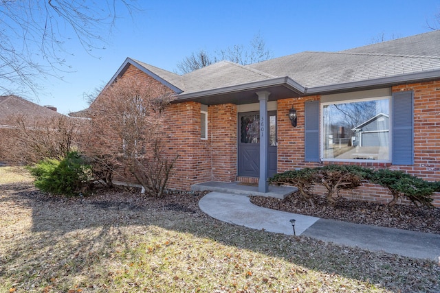 single story home featuring brick siding and roof with shingles