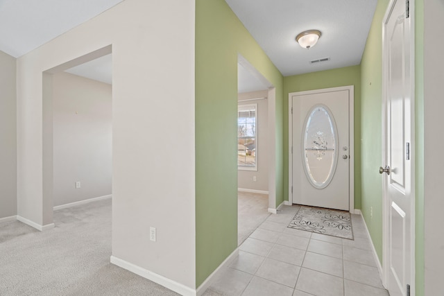 foyer entrance featuring light tile patterned flooring, visible vents, light colored carpet, and baseboards