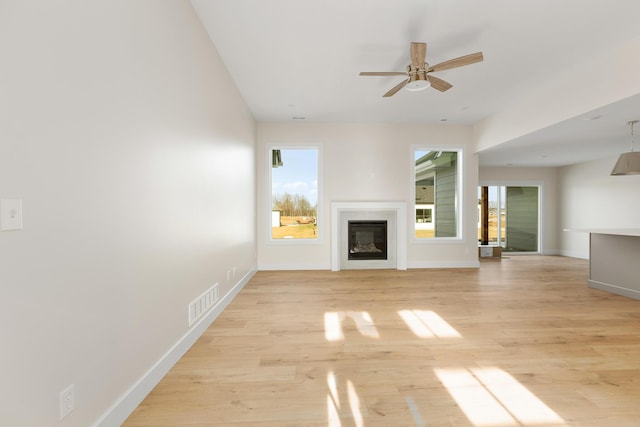 4509 Royal County Rd, Columbia, MO 65201 - unfurnished living room featuring light wood-type flooring, a glass covered fireplace, a ceiling fan, and plenty of natural light