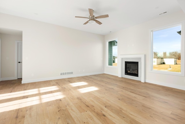 4509 Royal County Rd, Columbia, MO 65201 - unfurnished living room featuring a glass covered fireplace, light wood-style flooring, baseboards, visible vents, and ceiling fan