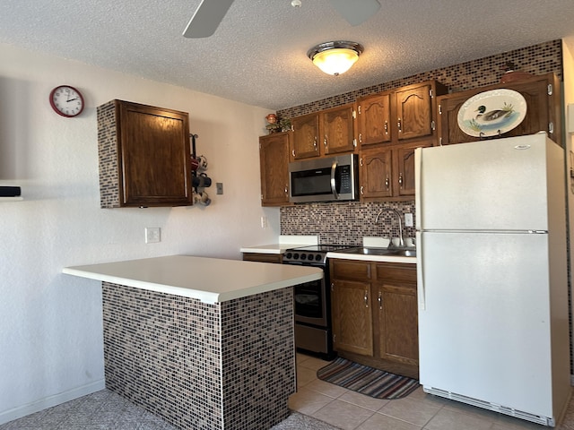 kitchen with light tile patterned flooring, sink, backsplash, white refrigerator, and electric range