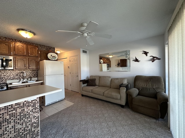 living room featuring ceiling fan, sink, a textured ceiling, and light tile patterned flooring