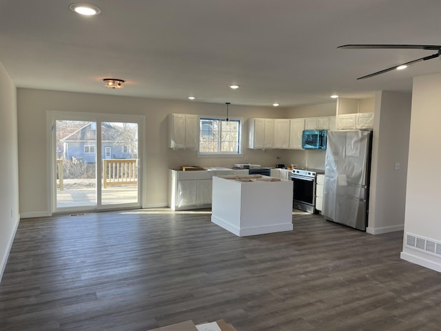 kitchen with visible vents, a kitchen island, dark wood finished floors, white cabinets, and appliances with stainless steel finishes