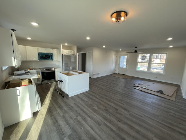 kitchen with a kitchen island, recessed lighting, stainless steel appliances, dark wood-style floors, and white cabinetry